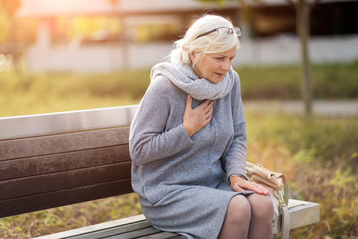 Woman on bench experiencing signs of a heart attack